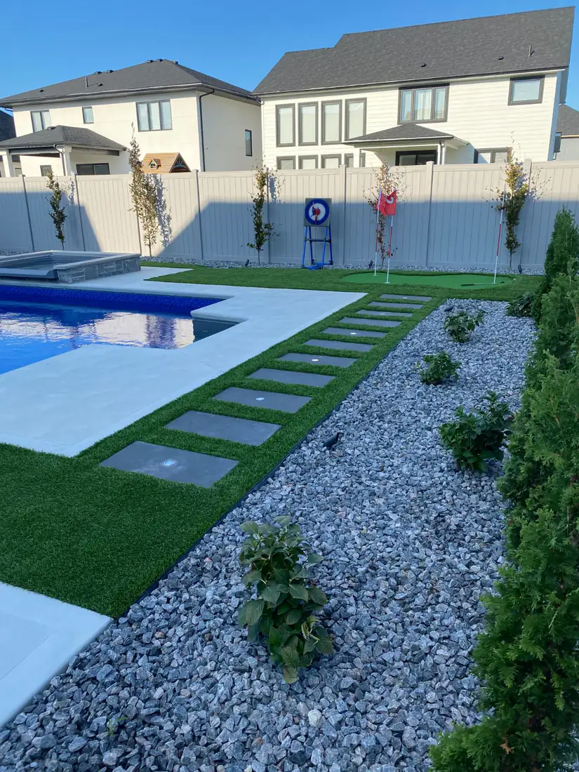 Concrete stepping pads through turf beside a stone bed