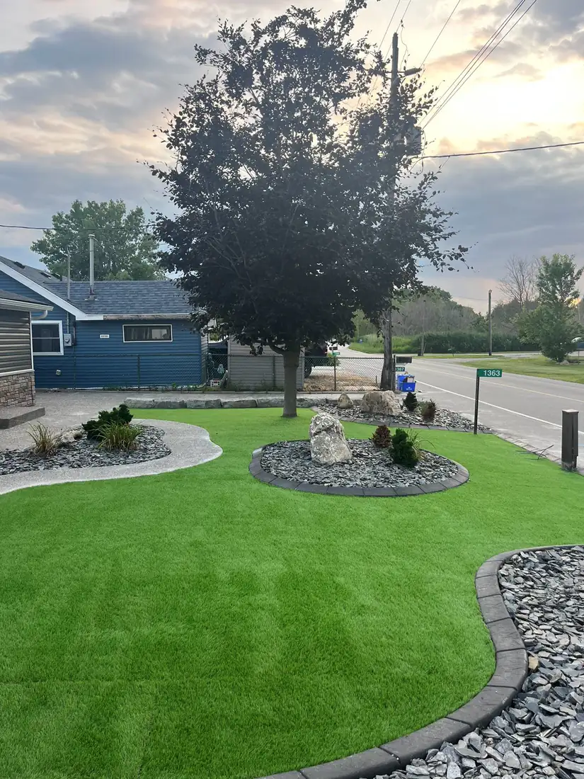 Newly laid sod around a tree and stone bed